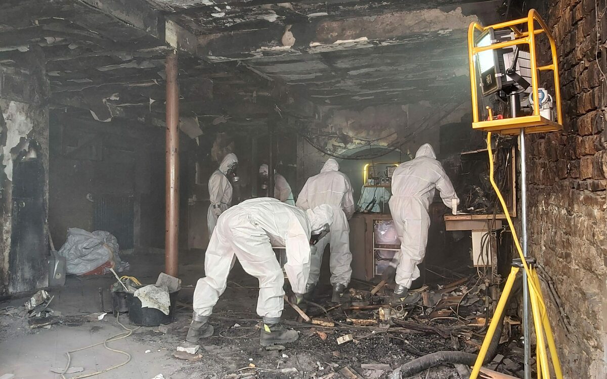 Feuerwehrleute mit schutzanzuegen am ausraeumen Feuerwehrleute mit schutzanzuegen am ausraeumen
